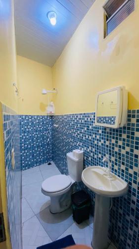 a blue tiled bathroom with a toilet and a sink at Pousada Amiga in Parintins