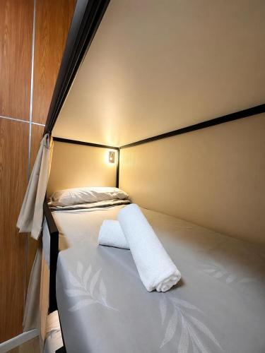 a bed with a white towel on top of it at As Baladas Hostel in Barro