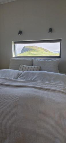 a bed in a room with a large window at Bygghamar in Stykkishólmur