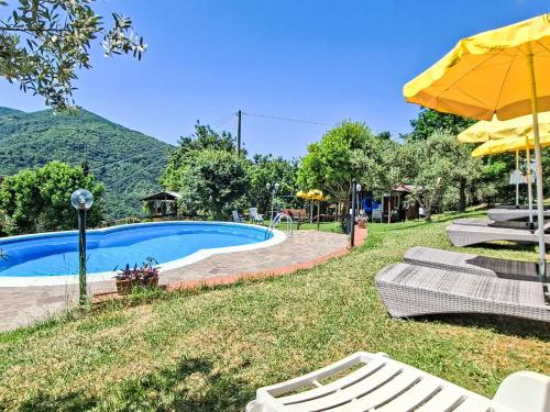 a swimming pool with two chairs and an umbrella at Holiday Home Luce by Interhome in Dicomano