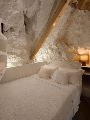 a bedroom with a white bed with a stone wall at La Cueva De Orel in Molinicos