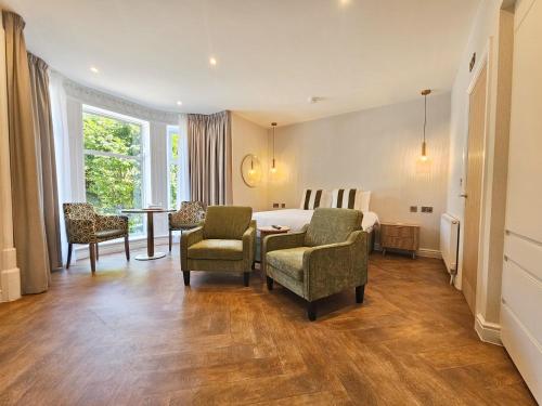 a hotel room with a bed and two chairs and a table at Derwent Manor Apartments & Rooms in Keswick