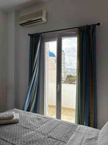 a bedroom with a bed and a window with curtains at Grecos in Perissa