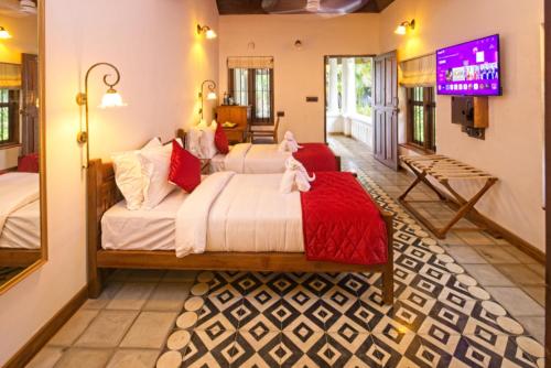 a bedroom with two beds and a tv in a room at Amritha Heritage in Trivandrum