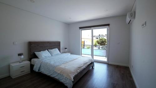 a bedroom with a bed and a large window at Moradia T4 Fernão Ferro in Fernao Ferro