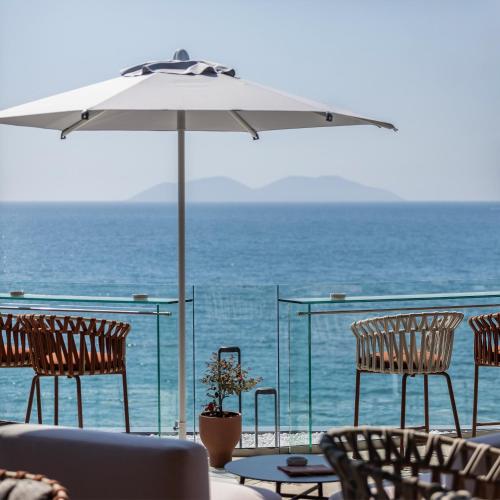 a patio with chairs and an umbrella and the ocean at Hotel Vlora Priam, Affiliated by Meliá in Vlorë