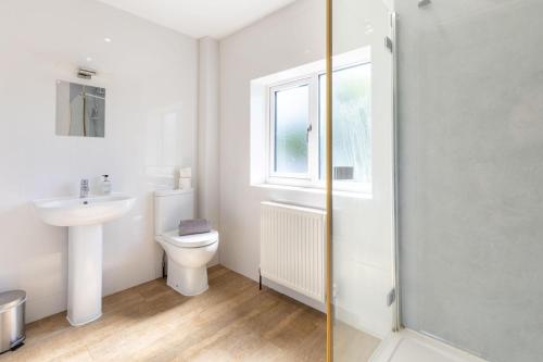 a bathroom with a toilet and a sink and a window at Saltkettle Sanctuary, Blakeney By Together Travel in Blakeney