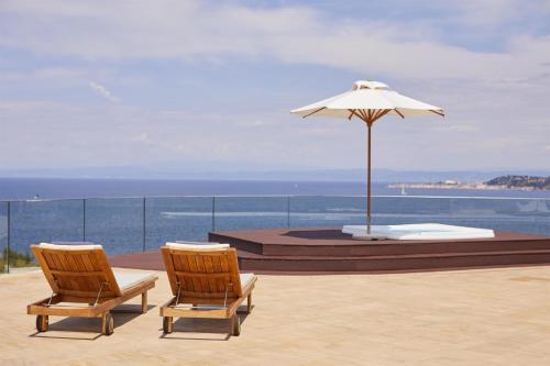 a pair of chairs and an umbrella on a balcony at Adriatic Istria Resort by Minor Hotels in Savudrija