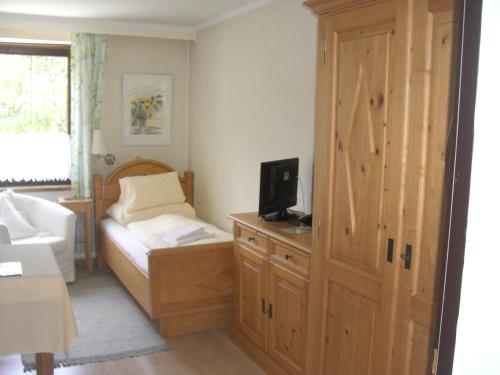 a bedroom with a bed and a cabinet with a television at Pension Landhaus Ingrid in Loich
