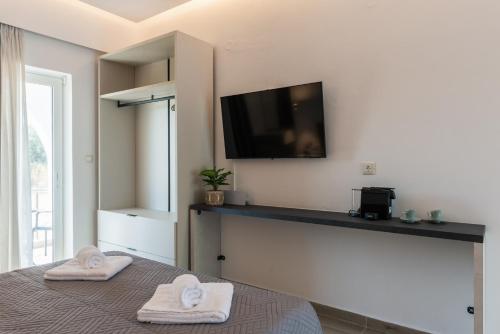 a bedroom with two towels on a bed with a flat screen tv at Aimilia Boutique Studio Kalathos in Kalathos