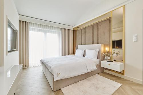 a bedroom with a white bed and a large window at Apartamenty Topollino in Częstochowa
