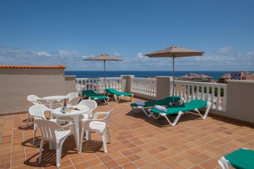 a patio with tables and chairs on a balcony at Hotiday Tenerife Norte in Puerto de la Cruz