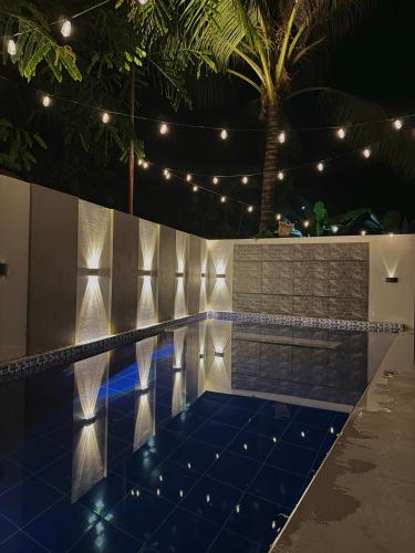 a swimming pool at night with lights and a palm tree at K&M Studio Suites Casa KM in Bingag