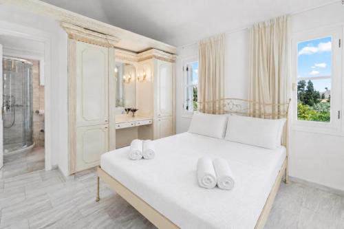 a white bedroom with a large white bed with white pillows at Villa Cypress with Private Pool and Mountain Views in Andros