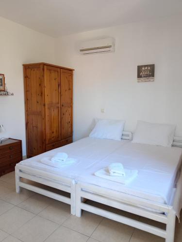 a white bed in a room with a wooden cabinet at Papas Studios in Skala Marion