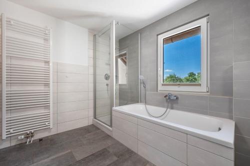 a white bathroom with a tub and a window at Fuchskreuzhof Simmersfeld in Simmersfeld