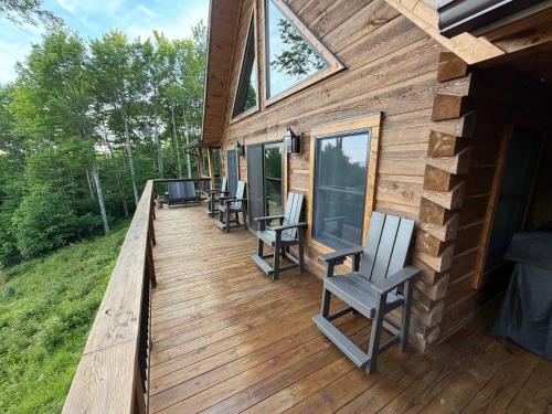 a wooden deck with chairs and windows on a cabin at Shawnee Ridge Lodge in Banner Elk
