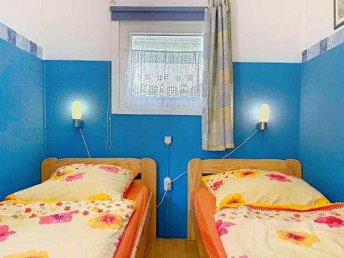 two beds in a room with blue walls and a window at Apartment Gabi-2 by Interhome in Wiek auf Rügen
