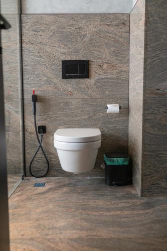 a bathroom with a toilet and a hose at Terratone Boutique Business Hotel in Kollam
