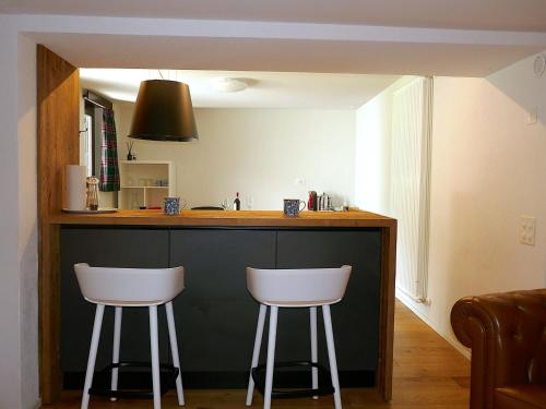 a kitchen with two white stools at a counter at Apartment Rina by Interhome in Olivone