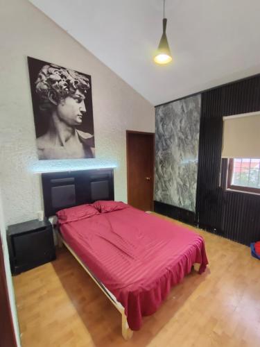 a bedroom with a red bed with a large painting on the wall at Casa al norte in Aguascalientes