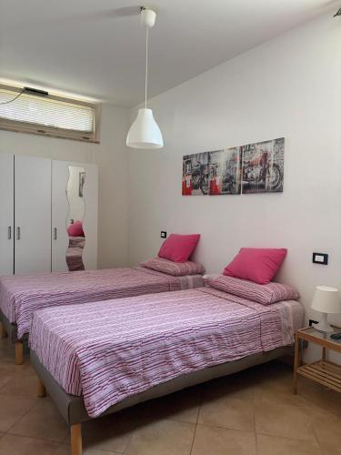 two beds in a room with pink pillows at Villa Andrea B&B in San Silvestro