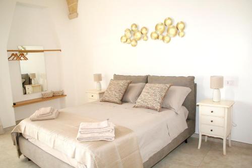 a white bedroom with a large bed and a mirror at Antica Stella in Specchia