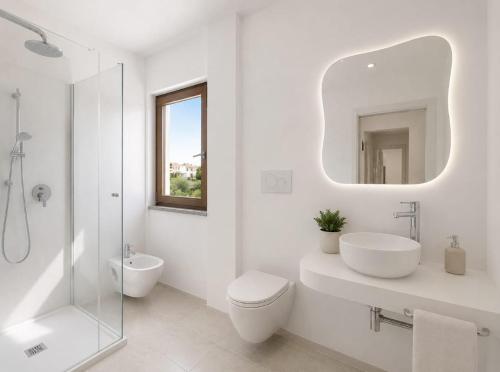 a white bathroom with a sink toilet and a mirror at Hotel Cala d'Oro - Hotel a pochi minuti dal mare di Cala Liberotto in Cala Liberotto