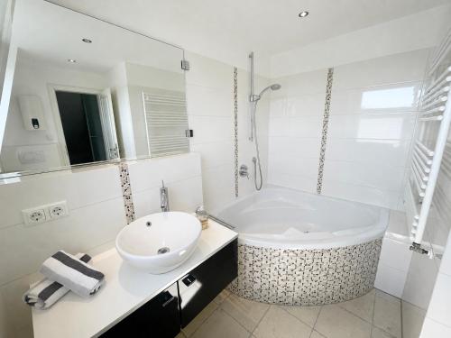 a white bathroom with a tub and a sink at Syltstyle 12 in Tinnum