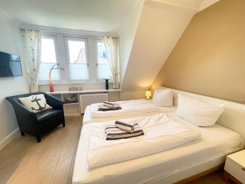 a hotel room with two beds and a chair at Syltstyle 12 in Tinnum