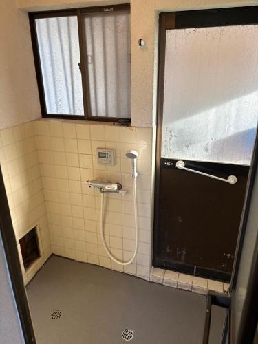 a shower with a hose in a bathroom at 海っぺりー作田 in Katakai