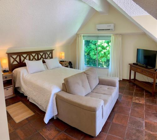 a bedroom with a bed and a couch and a window at Petit Chateau Hotel Boutique in Punta del Este