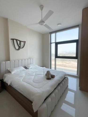 a large white bed in a room with a large window at Premium 2BHK Modern Design in Muscat