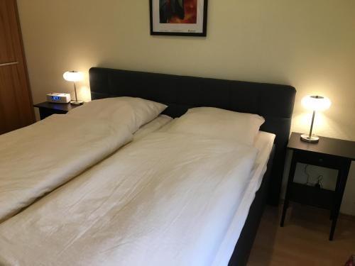 a bed with two white pillows and two tables with lamps at Ferienhaus Stausee Bitburg in Biersdorf am See
