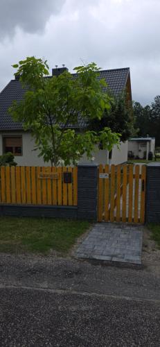 a yellow fence with a tree in front of a house at Sosnówka in Kolonowskie
