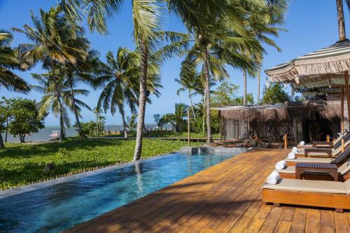 ein Pool in einem Resort mit Liegestühlen und Palmen in der Unterkunft Evva Pousada in Pôrto de Pedras