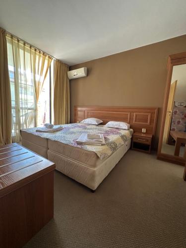 a bedroom with a large bed and a window at Hotel AVALON in Nesebar