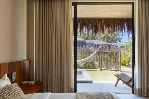 ein Schlafzimmer mit Bett und einer Glasschiebetür zur Terrasse in der Unterkunft Evva Pousada in Pôrto de Pedras