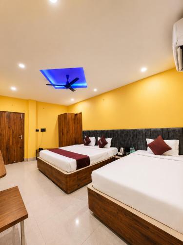 two beds in a room with yellow walls at Hotel Asha Palace By Basotel in Deoghar
