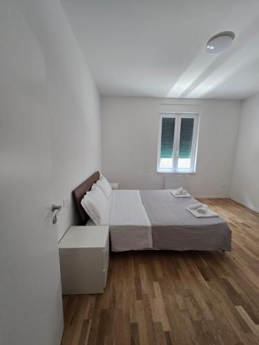 a white bedroom with a bed and a window at Appartamento Saffi in Faenza