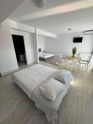 a white bedroom with a large bed and a table at Beside Gardens in Otopeni