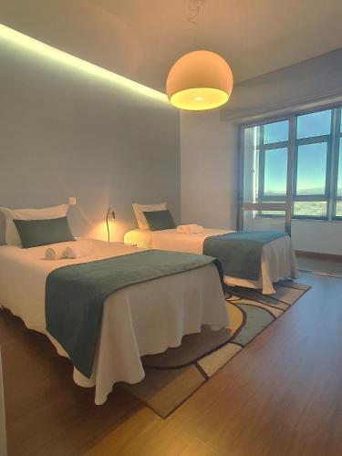 a bedroom with two beds and a large window at CAS Living Fátima in Fátima