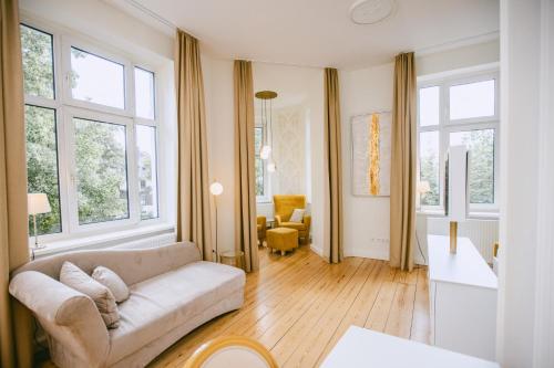 a living room with a couch and some windows at Johanniterhaus Wittenberg in Lutherstadt Wittenberg