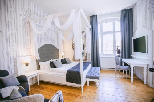 a bedroom with a canopy bed and a desk at Johanniterhaus Wittenberg in Lutherstadt Wittenberg