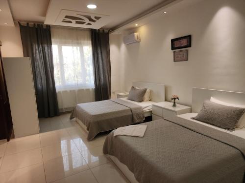 a hotel room with two beds and a window at Al-Amaari Gardens Compound 3091 in Irbid