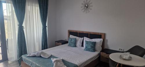 a bedroom with a bed with blue curtains and a table at Villa Eliada in Tuzla