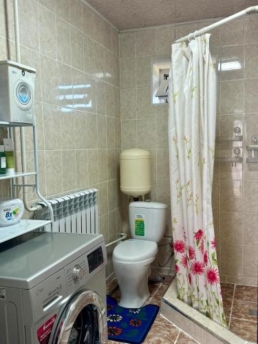a bathroom with a toilet and a washing machine at Ilgiz Guest House in Bokonbayevo