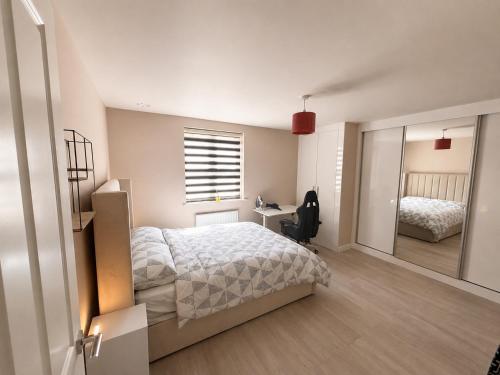 ein Schlafzimmer mit einem Bett, einem Schreibtisch und einem Spiegel in der Unterkunft Bright, Spacious Double Room in a Modern Flat in Edmonton