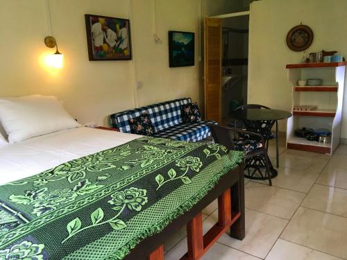 a bedroom with a bed and a couch in it at Creole Cottage in Calibishie