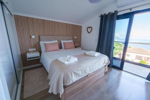 a bedroom with a bed with pink pillows and a large window at Eva's house in São Vicente